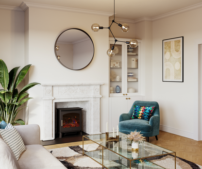 A styled living room interior featuring a white fireplace with a black electric insert, a round black-framed mirror, a teal velvet armchair with a colorful patterned pillow, a glass coffee table, and a large potted plant.
