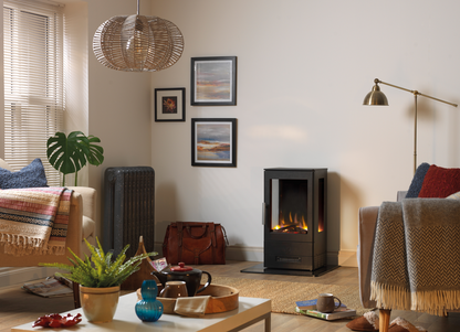 A modern black floor fireplace with a glowing fire, set in a cozy, well-lit living room with a sofa, armchair, coffee table, and wall art.