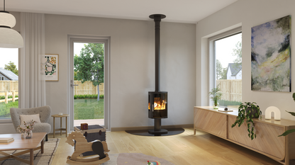 A modern black floorless wood-burning stove with a tall chimney pipe stands in a bright, contemporary living room with light wood floors and neutral walls.