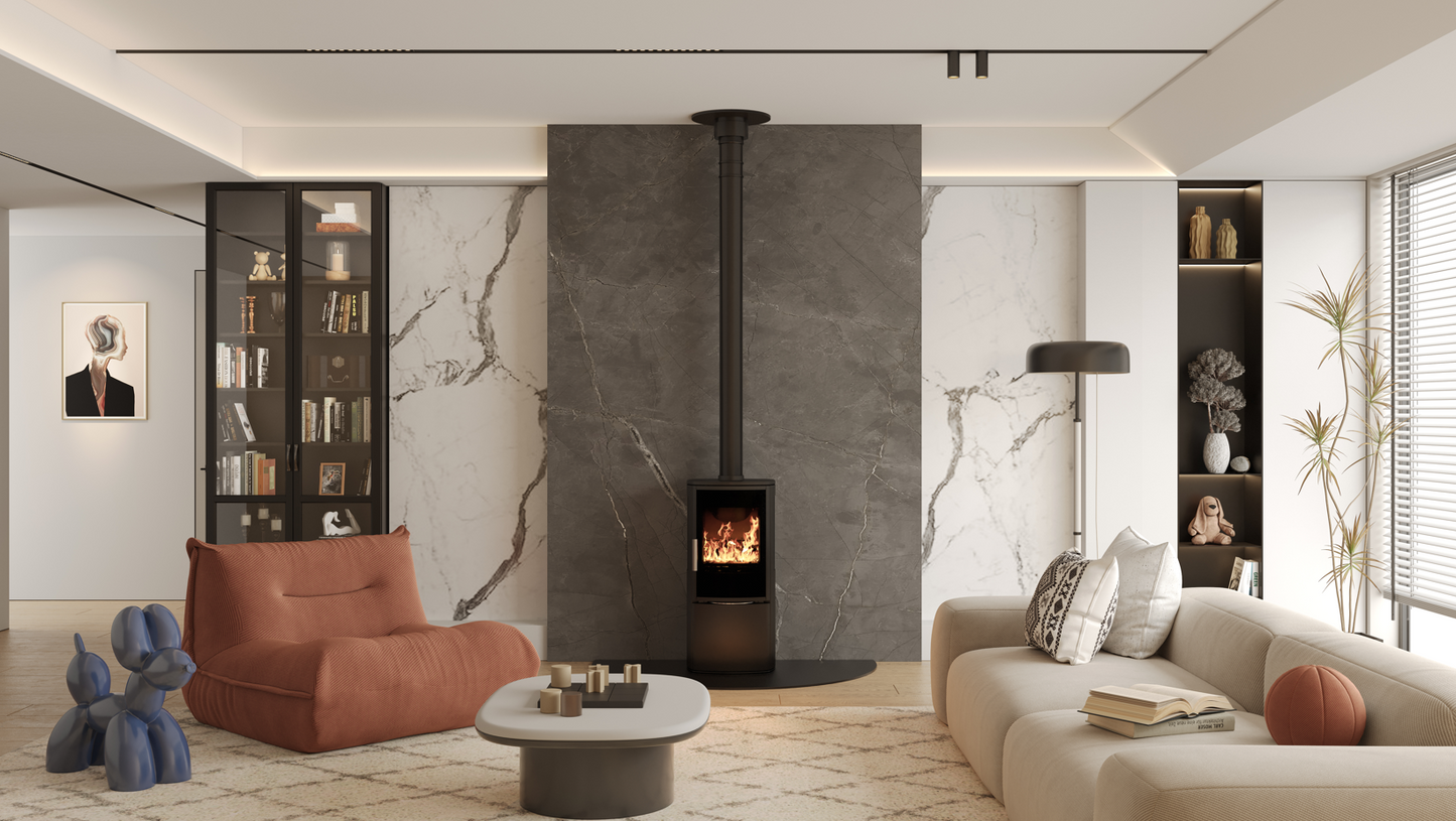 ACR Neo XC. A modern living room featuring a black wood-burning stove with a tall black chimney pipe set against a large dark gray stone wall. The room is styled with a terracotta armchair, a cream sofa, a round coffee table, and marble-patterned accent walls.