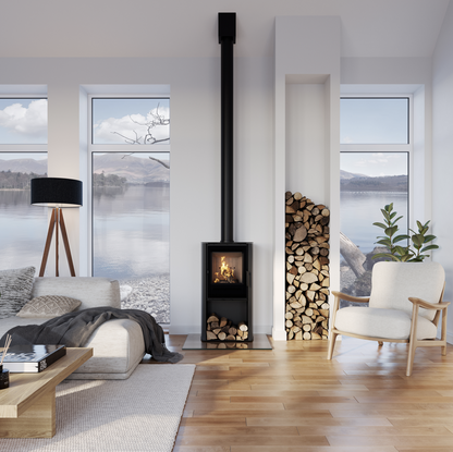 ACR Osprey 5kW. A modern black wood-burning stove with a tall chimney pipe stands in a bright, contemporary living room with hardwood floors, a sofa, and a chair, with a stack of firewood beside it.