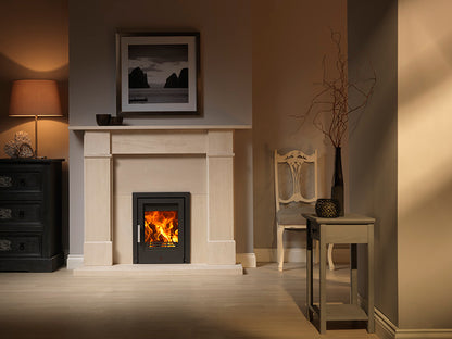 ACR Tenbury t400 ECO Inset Stove. A modern black fireplace insert with a glowing orange fire, set within a white stone mantel in a styled living room.