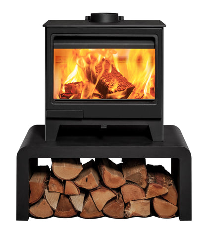 A black wood-burning stove with a glass front door sitting on a bench with logs beneath showing a bright fire and logs, isolated on a white background.
