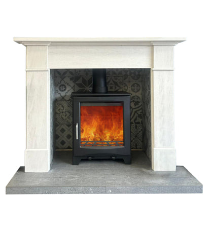 A black wood-burning stove with a glowing orange fire, set inside a white stone fireplace mantel with a gray tiled backing and a gray hearth.
