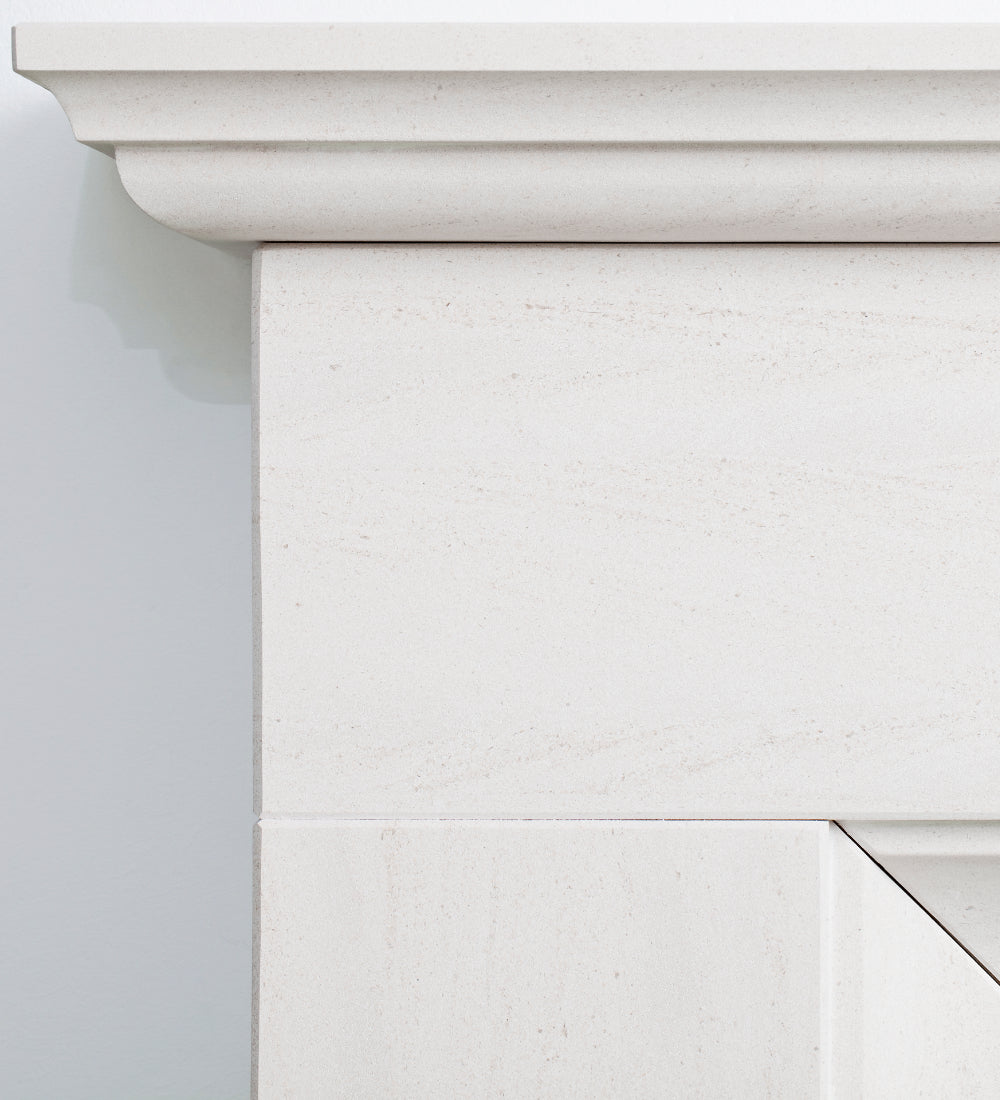 Close-up detail of a white stone fireplace mantel showing the carved top ledge and textured stone surface.
