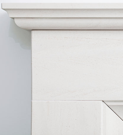 Close-up detail of a white stone fireplace mantel showing the carved top ledge and textured stone surface.