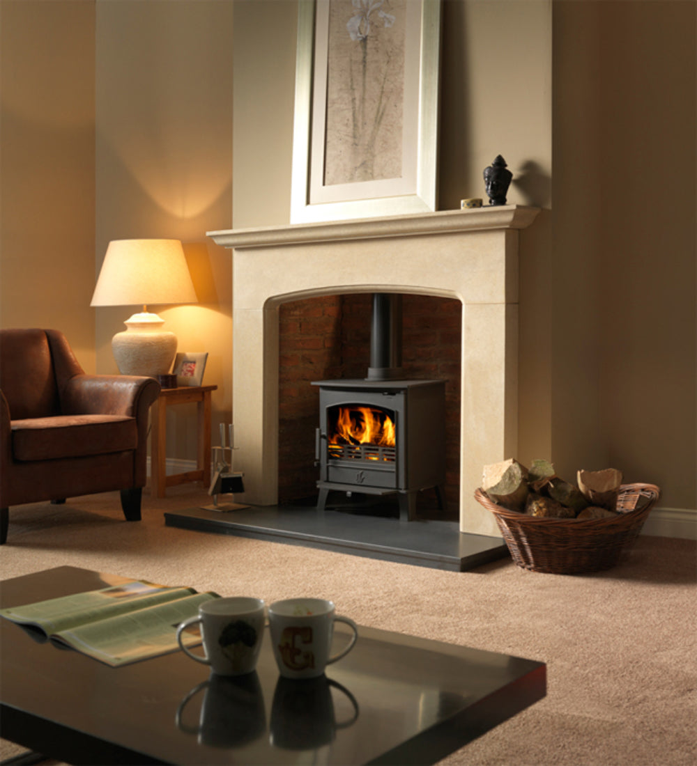 Limestone fireplace in a lounge setting with wood burner log basket.