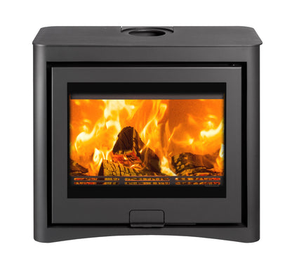 A modern black freestanding square wood-burning fireplace with a glass viewing window showing bright orange and yellow flames, and an open lower shelf holding stacked firewood logs, isolated on a white background.