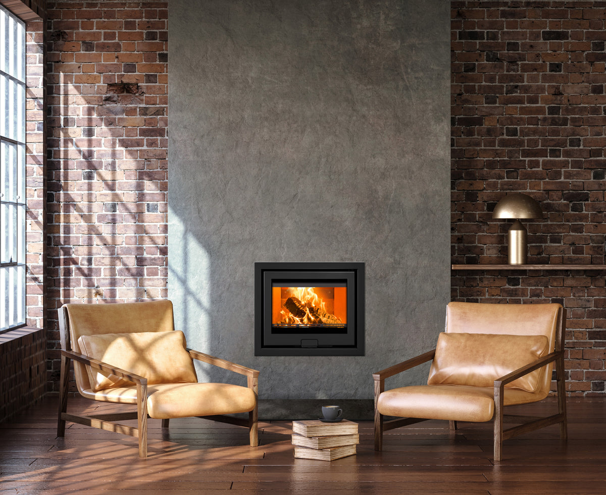 A modern black fireplace insert with a glowing fire, set in a rustic room with exposed brick walls, two tan leather armchairs, and a concrete wall panel behind it.