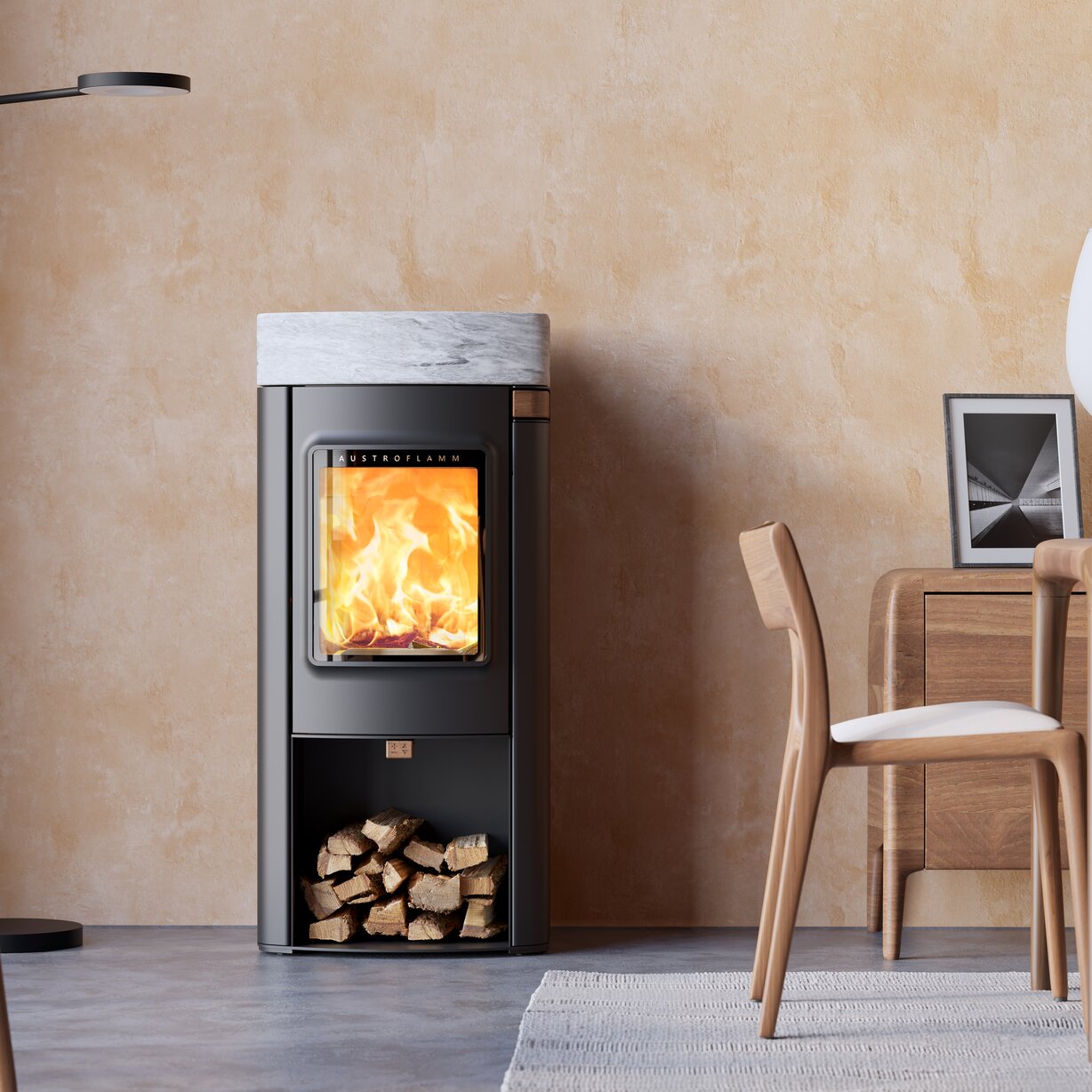 A modern black wood-burning stove with a white marble top and a visible fire inside, staged in a minimalist room with a textured beige wall, a wooden chair, and a side table.