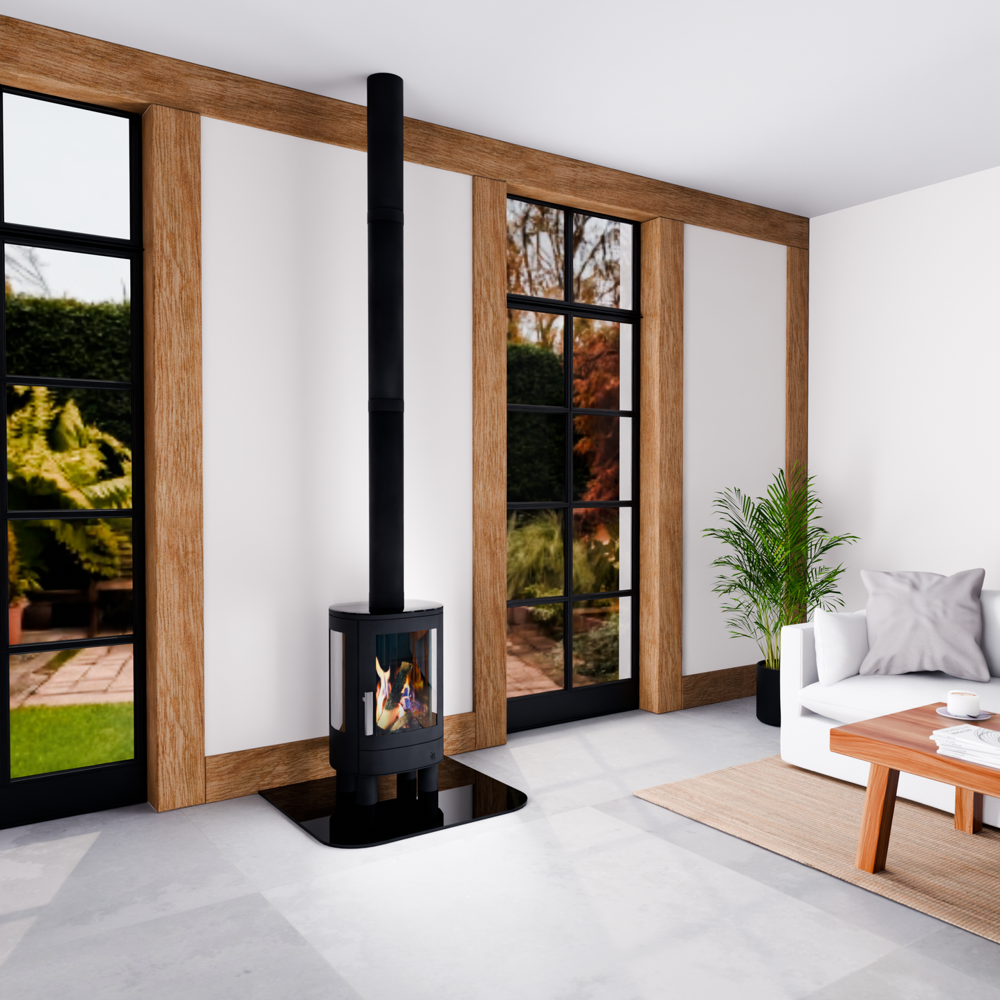 A modern black wood-burning stove with a tall chimney pipe stands in a contemporary living room with white walls, wooden trim, large windows, a white sofa, and a potted plant.