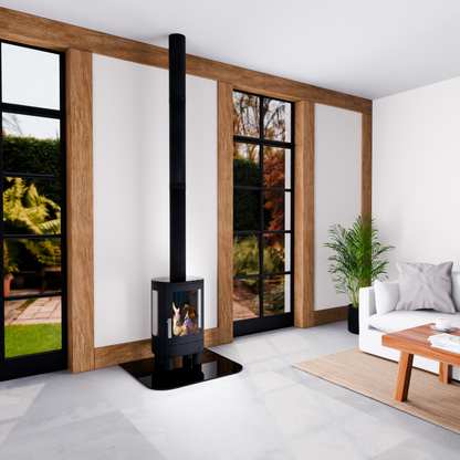 A modern black wood-burning stove with a tall chimney pipe stands in a contemporary living room with white walls, wooden trim, large windows, a white sofa, and a potted plant.