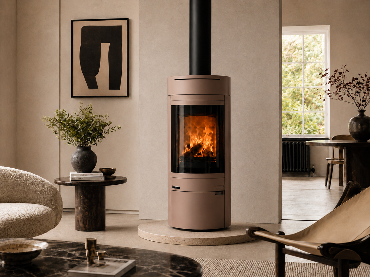A modern round wood-burning stove with a warm fire visible inside, set in a stylish, neutral-toned living room.
