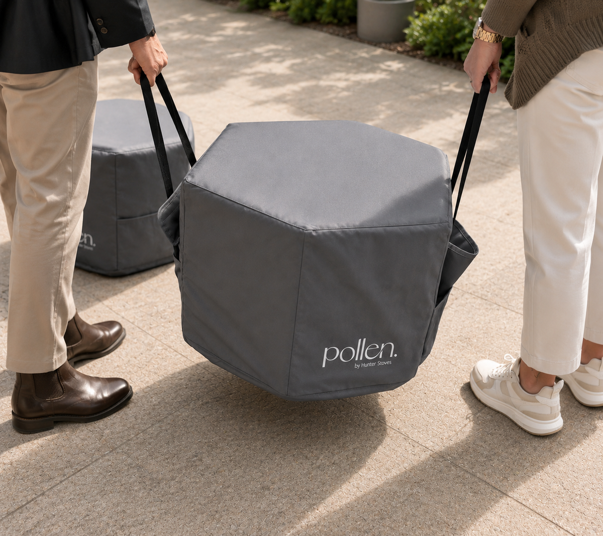 Two people lifting a grey 'pollen' hex cover on a patio.