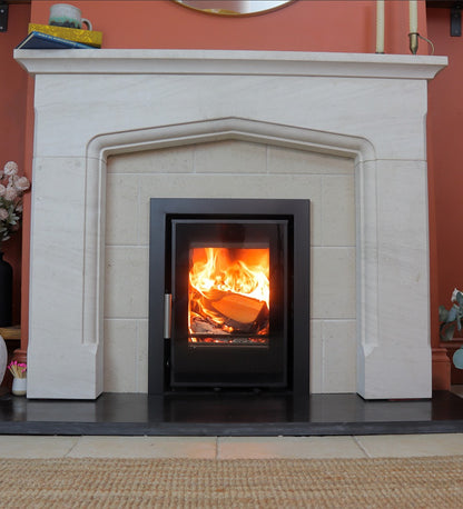 Wood-burning stove in a white fireplace with a red wall background