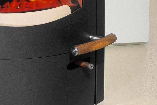 Close-up of a black metal door handle with a curved wooden grip and a silver metal end cap, mounted on a black door next to a light-colored wall.
