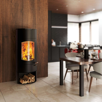A modern black wood-burning stove with a glowing fire visible through a glass front, set against a dark wood wall in a contemporary dining and living room interior.