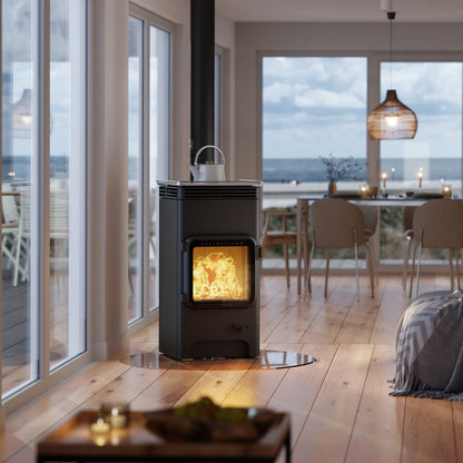 Modern living room with a wood stove and large windows overlooking the ocean.