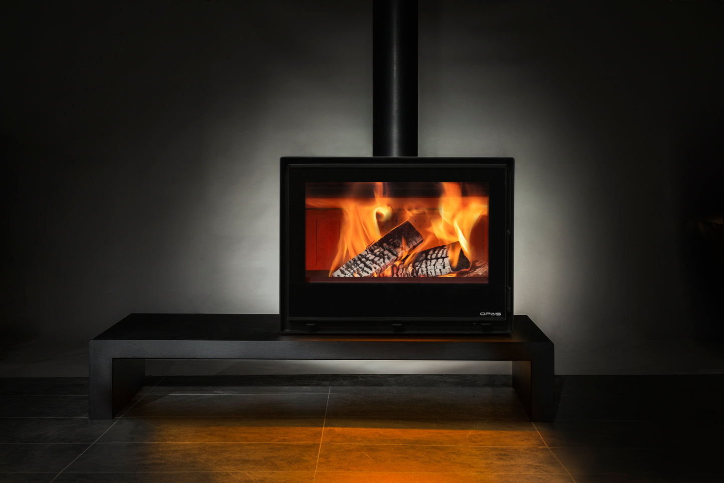 Wood-burning Octave Opus stove with flames inside, set against a dark background