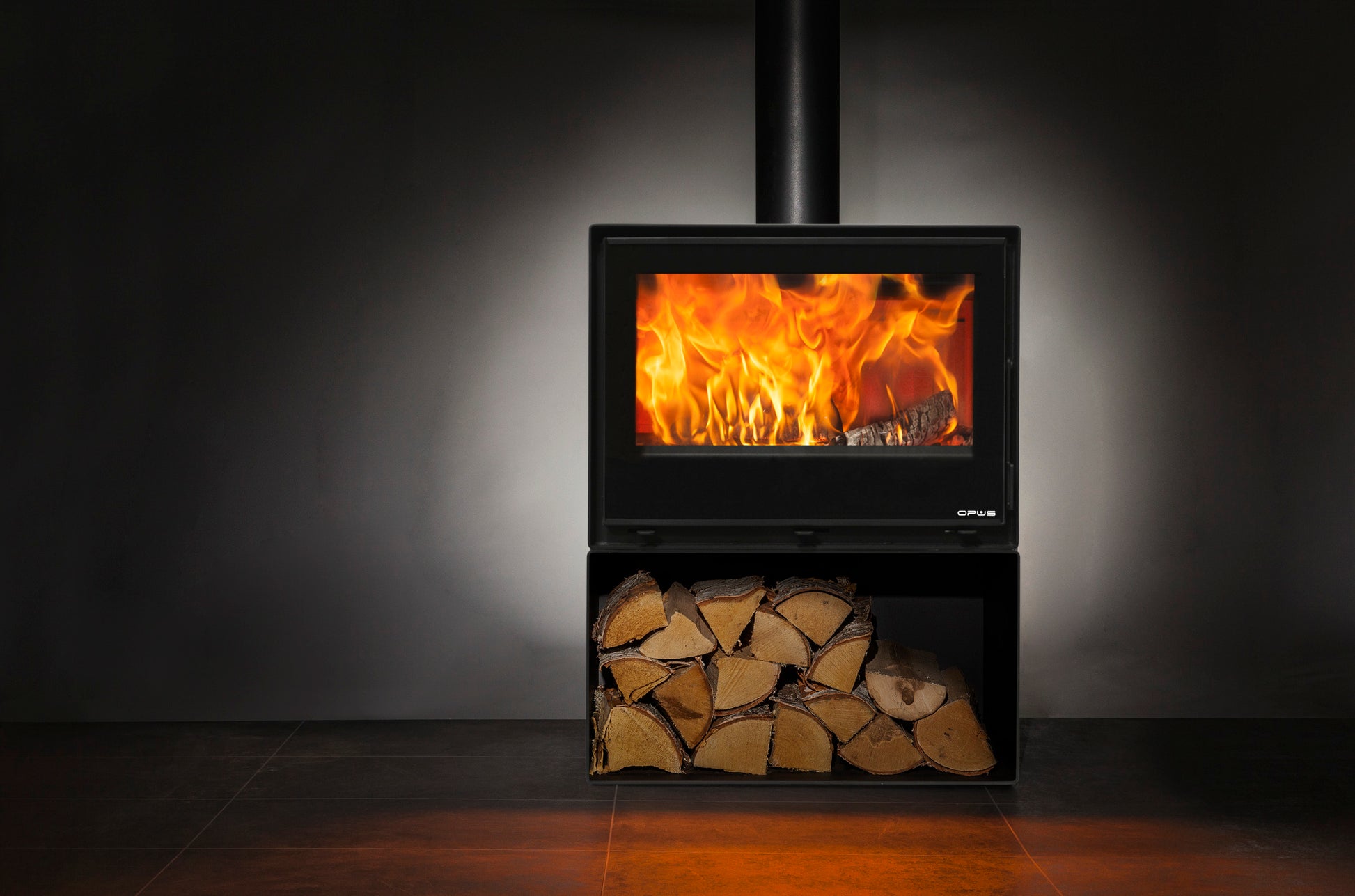 Opus Octave Wood-burning stove with glowing flames and stacked logs against a dark background