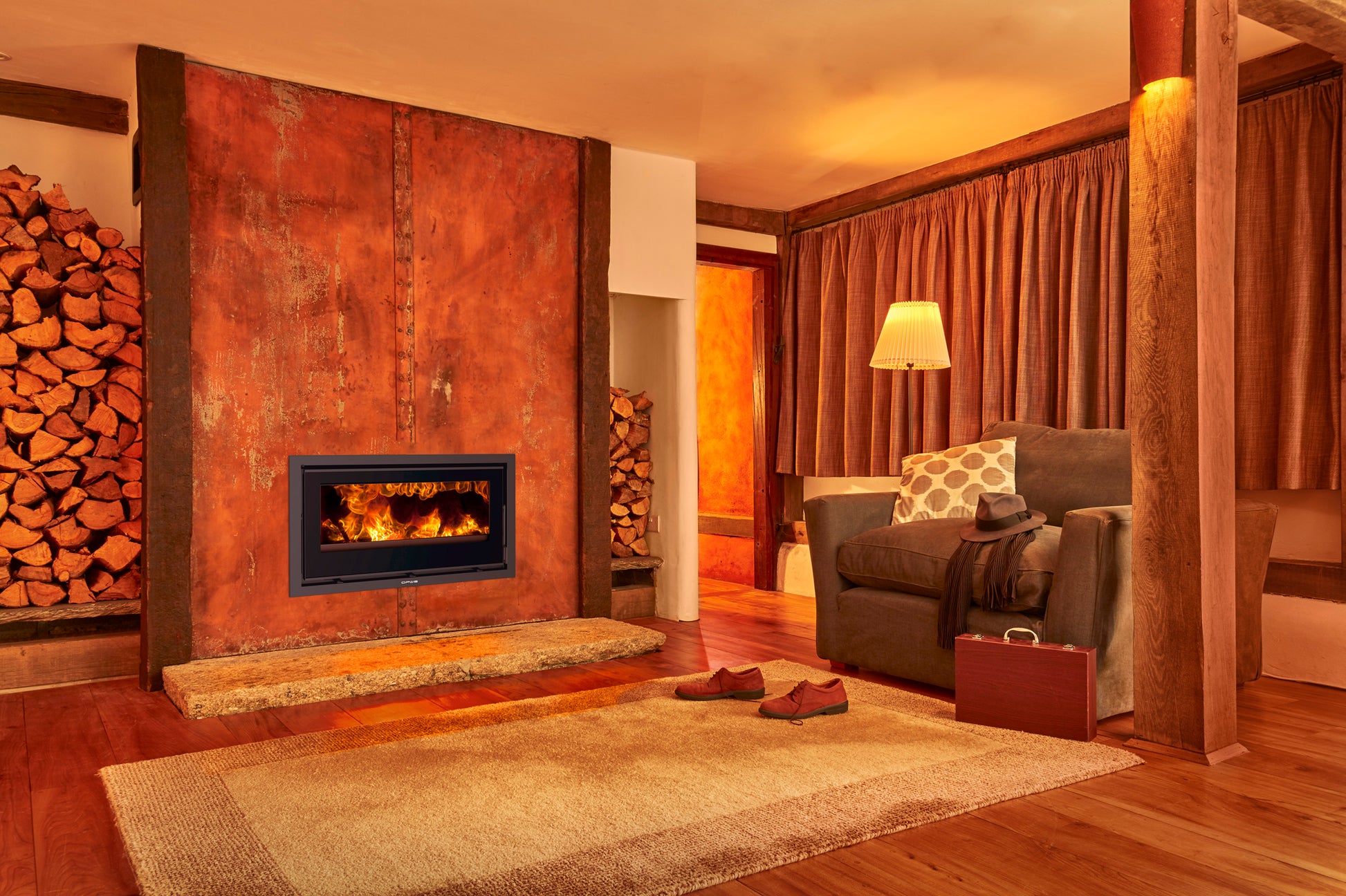 Cozy living room with a Octave Opus fireplace, wooden logs, and a sofa.