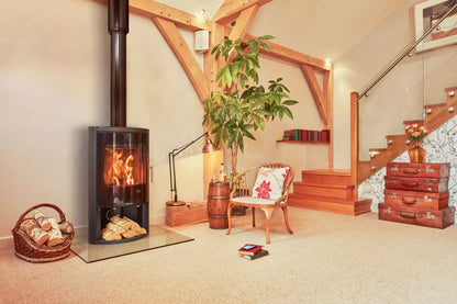 Living room with a Opus GLS wood stove, chair, and decorative items.