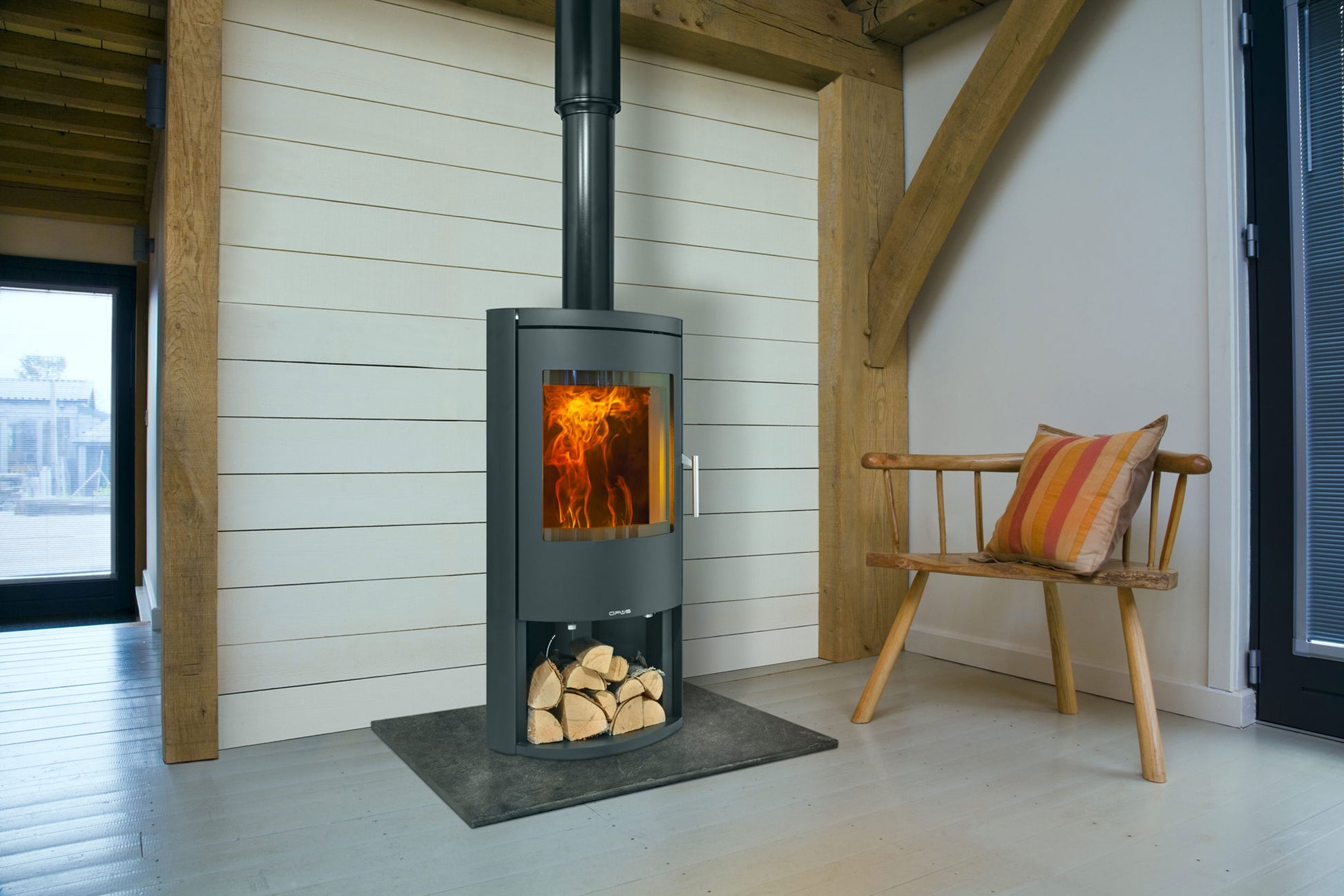 Opus Wood-burning stove in a modern room with wooden beams and a bench.