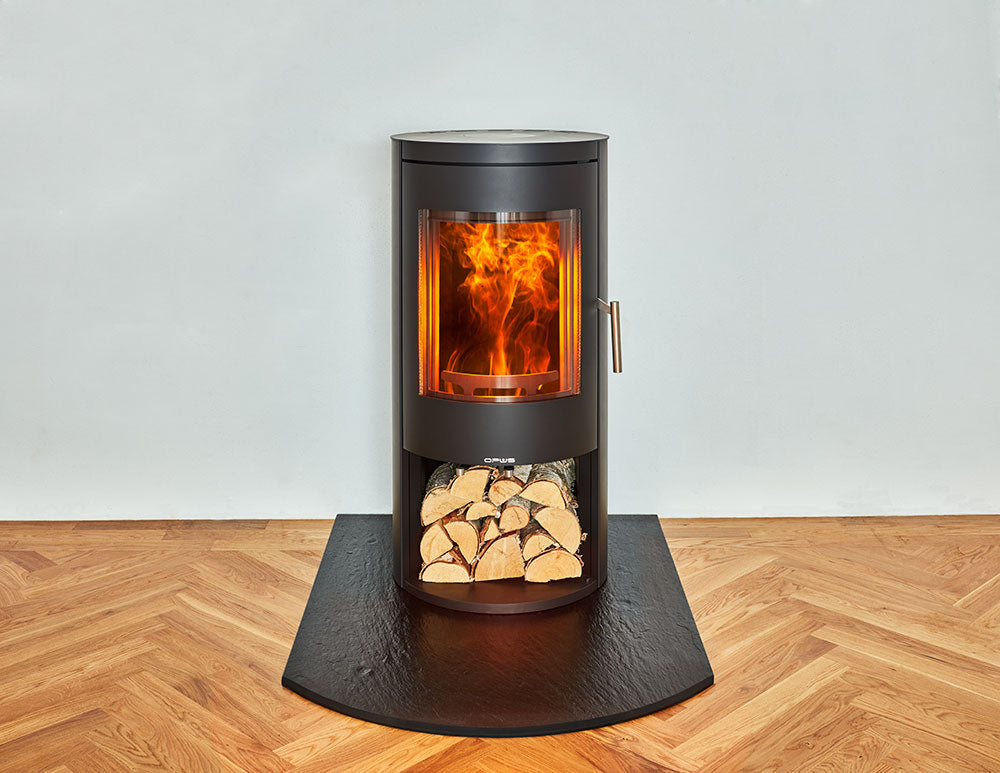 Opus Melody Wood-burning stove with glowing interior and log store beneath on a slate Hearth