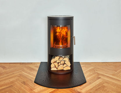 Opus Melody Wood-burning stove with glowing interior and log store beneath on a slate Hearth