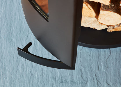 Close-up of a black metal firewood holder against a light blue wall.