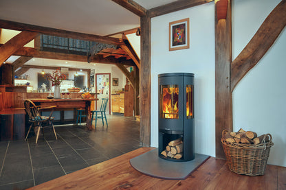 Opus Trio Wood-burning stove in a rustic room with wooden beams and a dining area