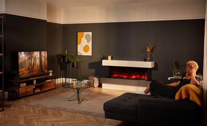 Rayburn Stratus 125-39 Tru View Electric Fire. Modern living room with a woman sitting on a sofa, TV, and fireplace.