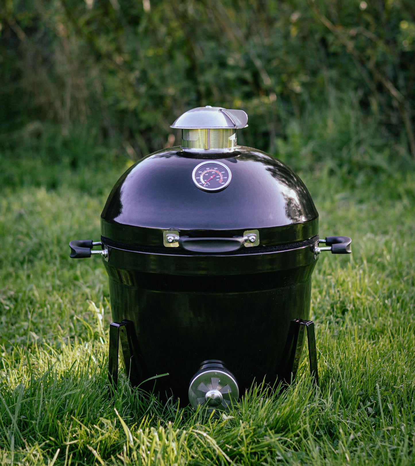 Salamanda Little Cayuga Black barbecue grill on grass with a blurred green background