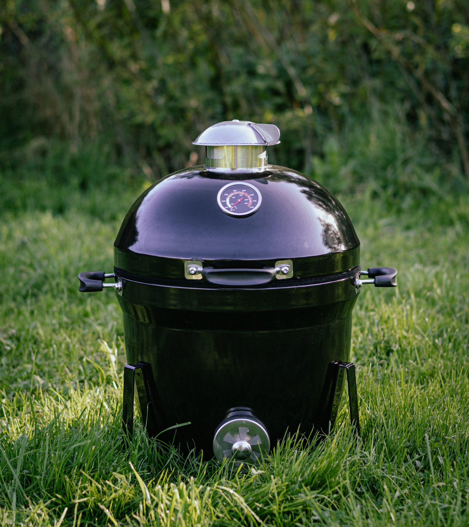 Salamanda Little Cayuga Black barbecue grill on grass with a blurred green background
