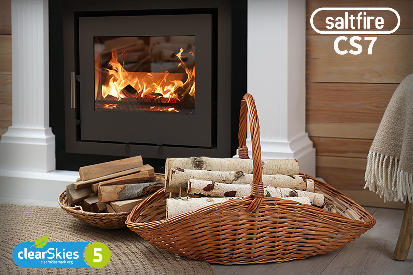 Saltfire Windset Wood-burning stove with fire lit, surrounded by baskets of wood, in a home setting.