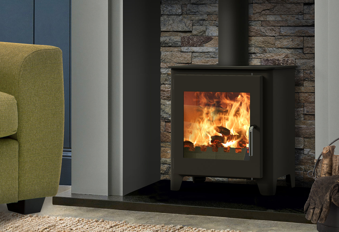Saltfire ST1 Vision Wood burning stove in a room with a stone wall and green armchair.
