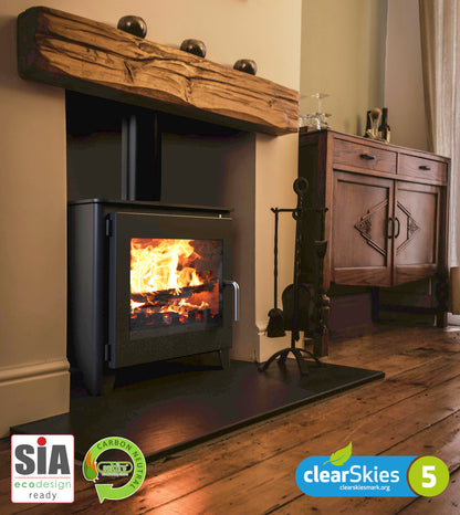 Saltfire ST3 Wood-burning stove with flames lit, surrounded by wooden furniture in a room.