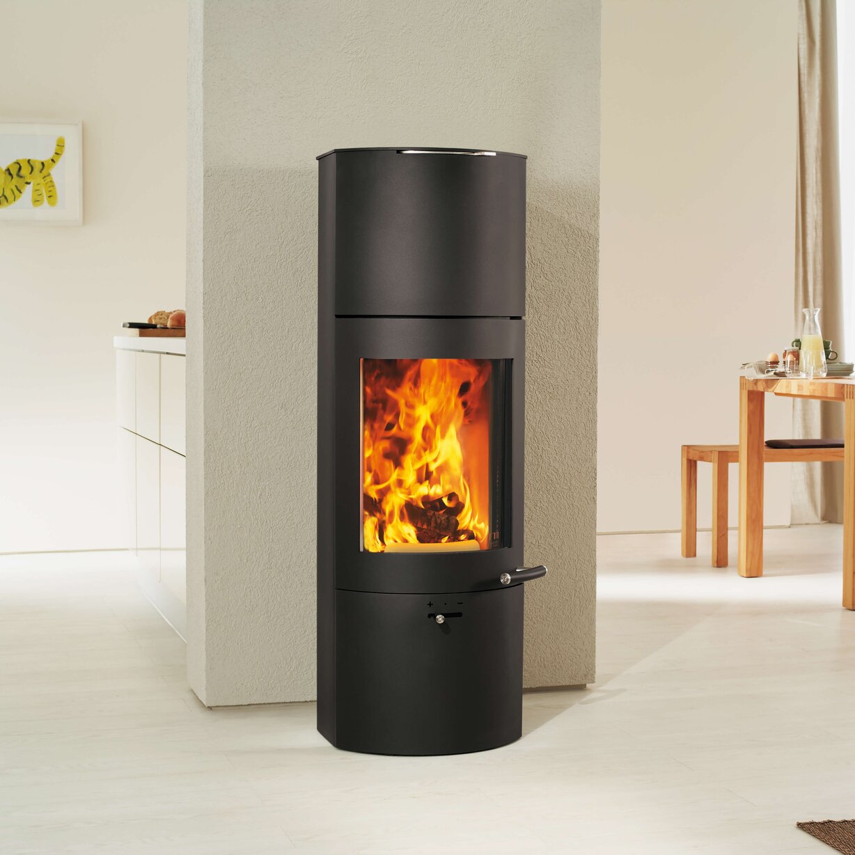 A modern black cylindrical wood-burning stove with a visible orange fire, set against a minimalist beige interior background.