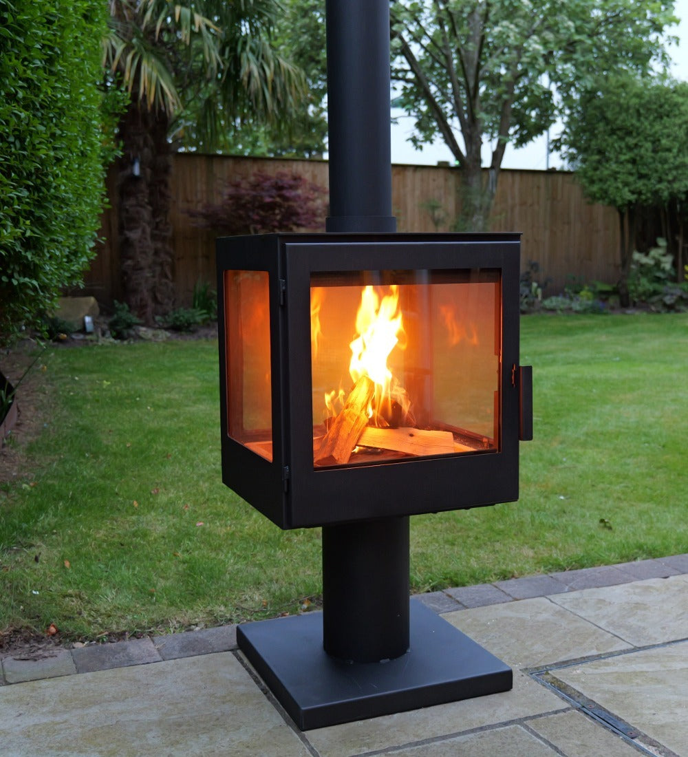 Outdoor fireplace with flames on a patio area in a garden setting