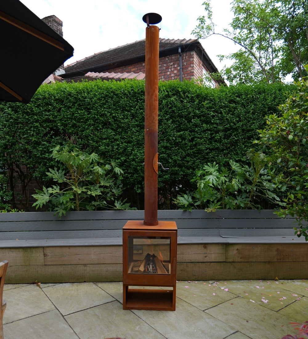 Wood-burning stove on a patio with a garden and house in the background